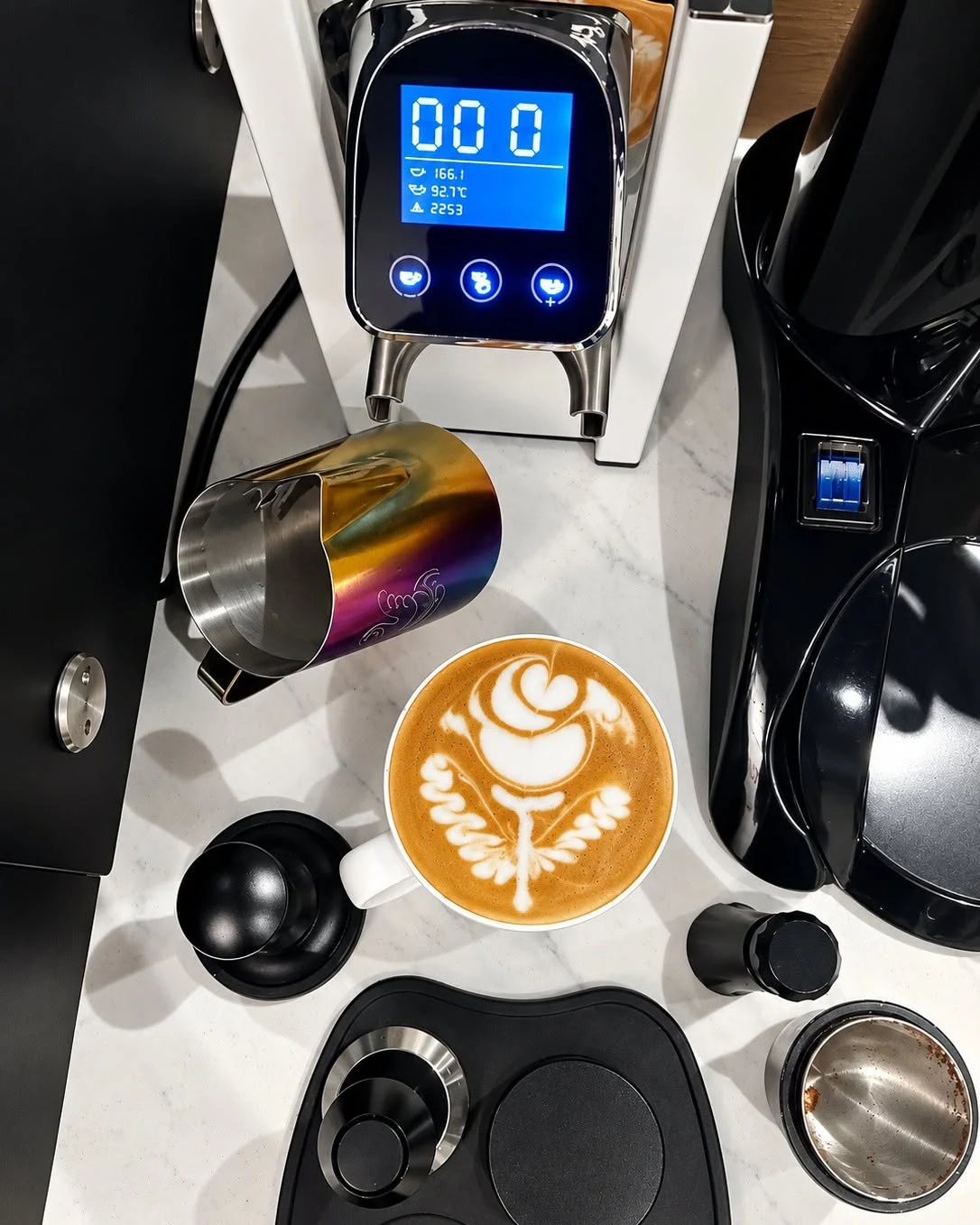 Intricate latte art in a cup beside an espresso machine